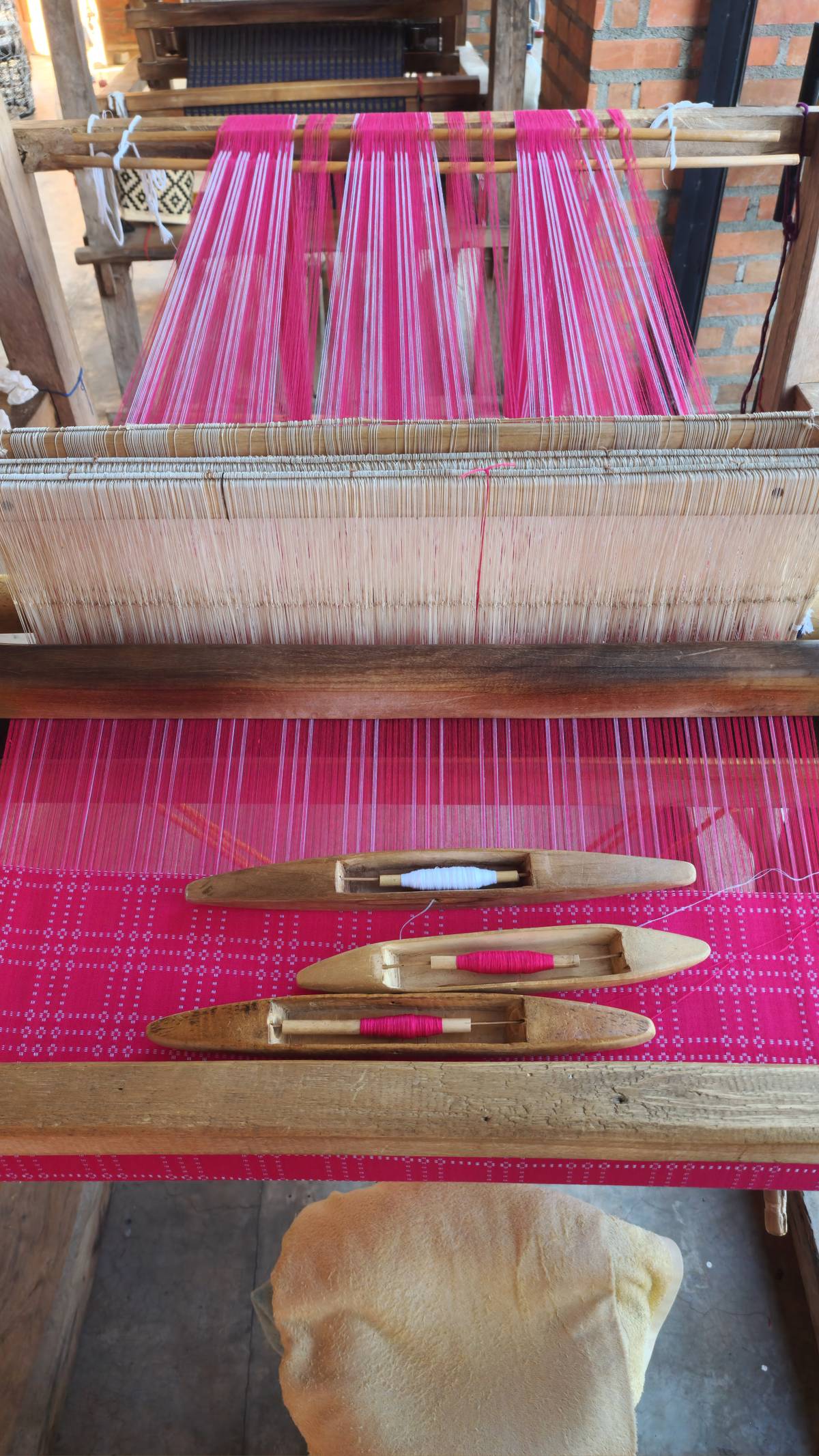 A half-finished pinilian textile still on the wooden loom at the weaving center.